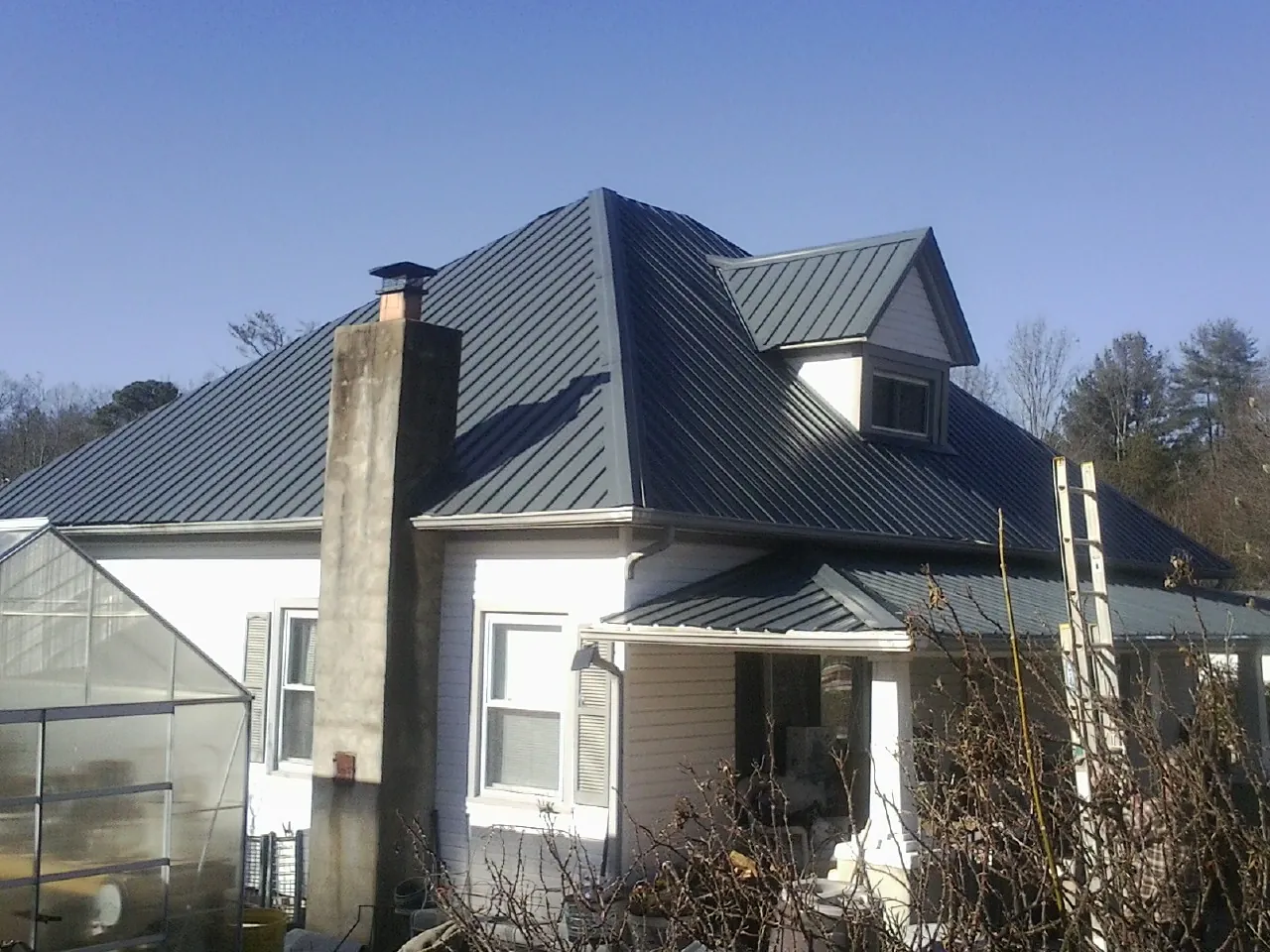 Dark blue standing seam metal roof on a white farmhouse with dormer — Slate & Tile Roof Repair by Roofing Brothers in Macclesfield