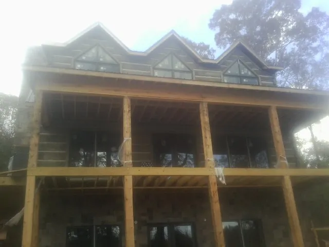 Dormers and porch framing on a large log home under construction — Roof Coating work by our crew in Macclesfield