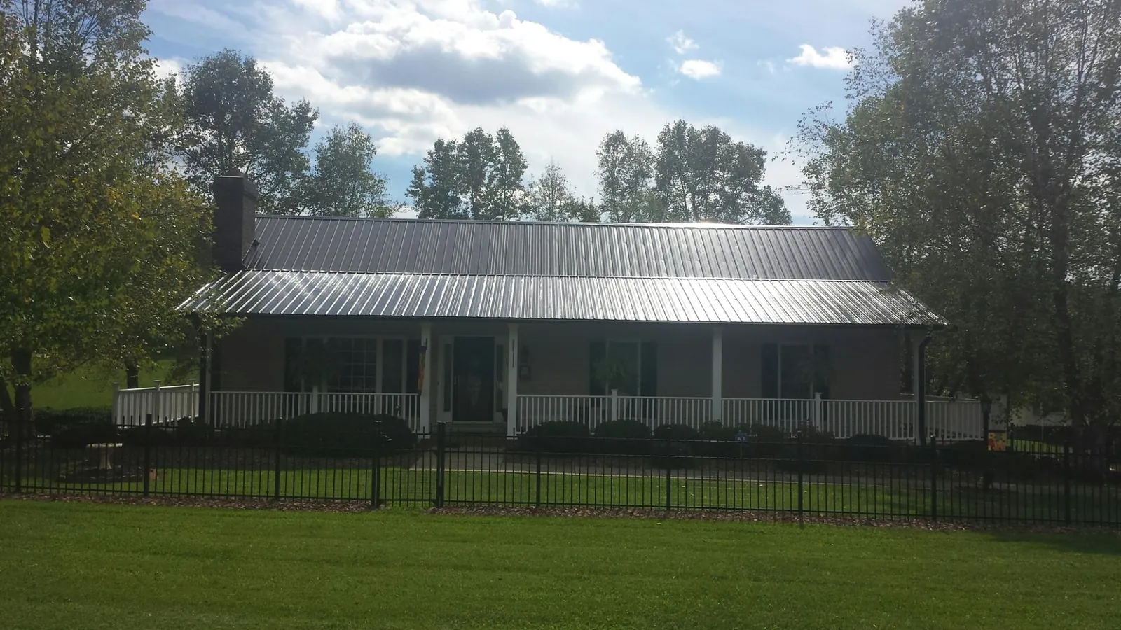 Gray metal roof on a brick ranch with a full width front porch — Gutter Guard Installation work by our crew in Macclesfield